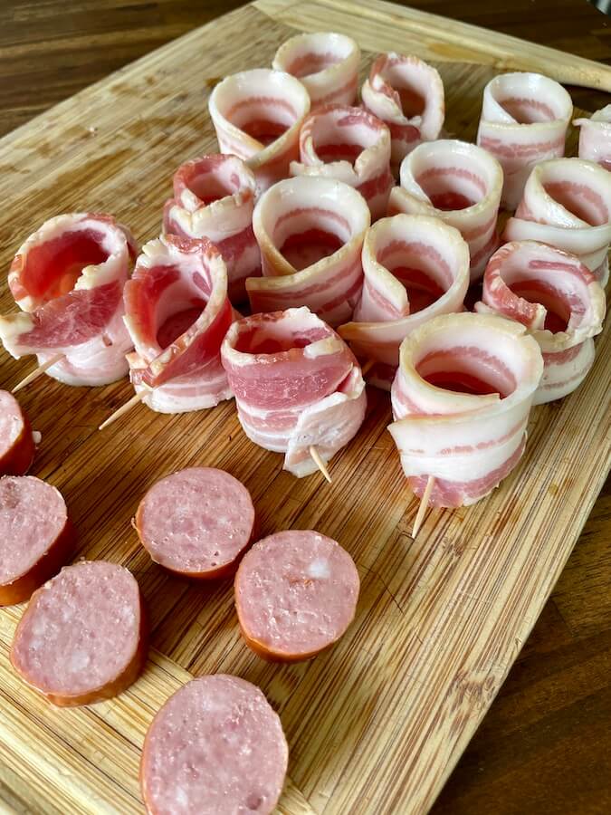 slices of sausage wrapped in bacon to form a bacon shot glass