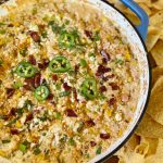 smoked street corn dip in a cast iron skillet with tortilla chips