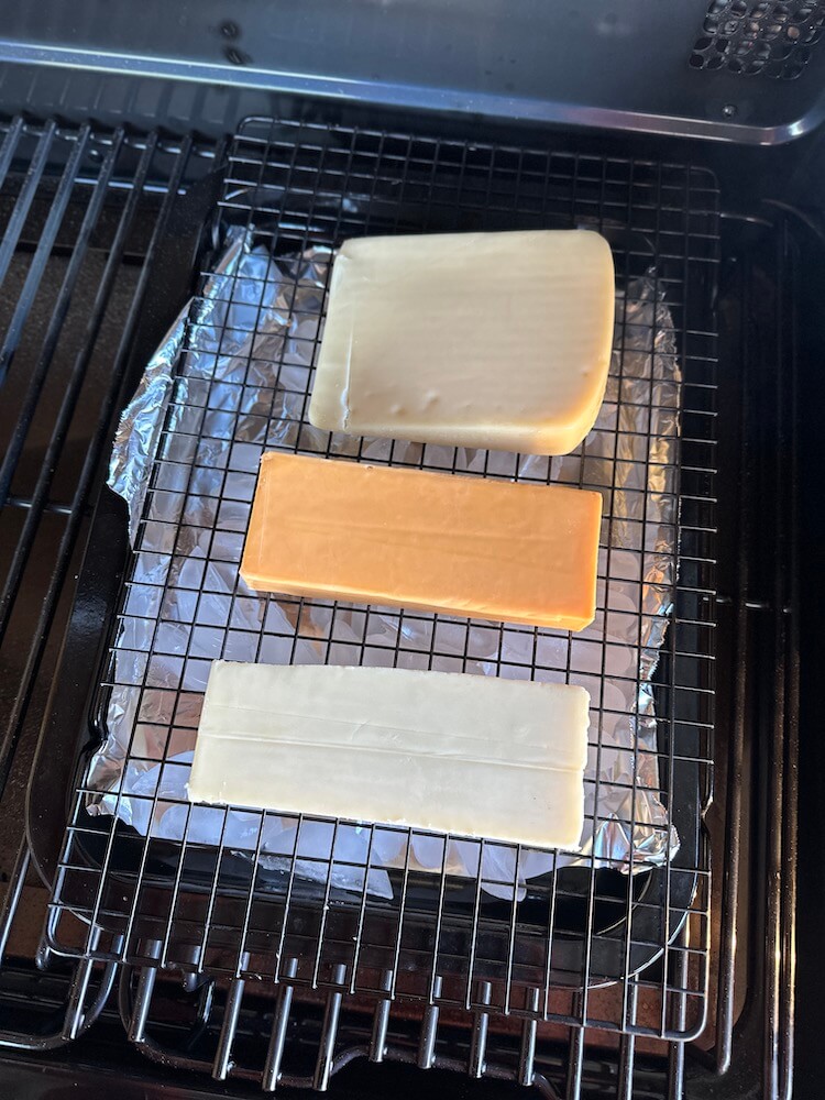 3 blocks of cheese on a wire rack on a Traeger grill