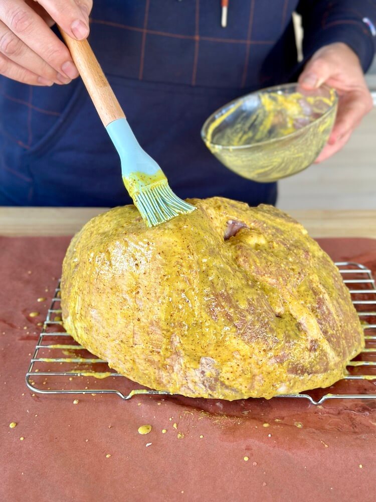 putting a mustard binder on a ham