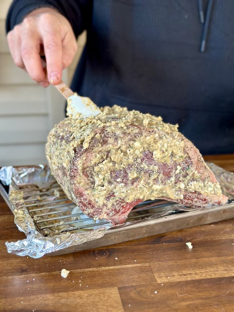 spreading a horseradish butter on the outside of a rib roast