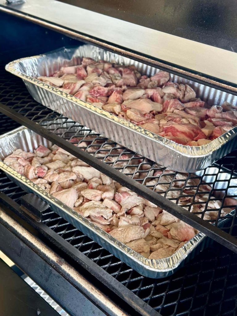 smoking large aluminum pans of brisket trimmings on a smoker