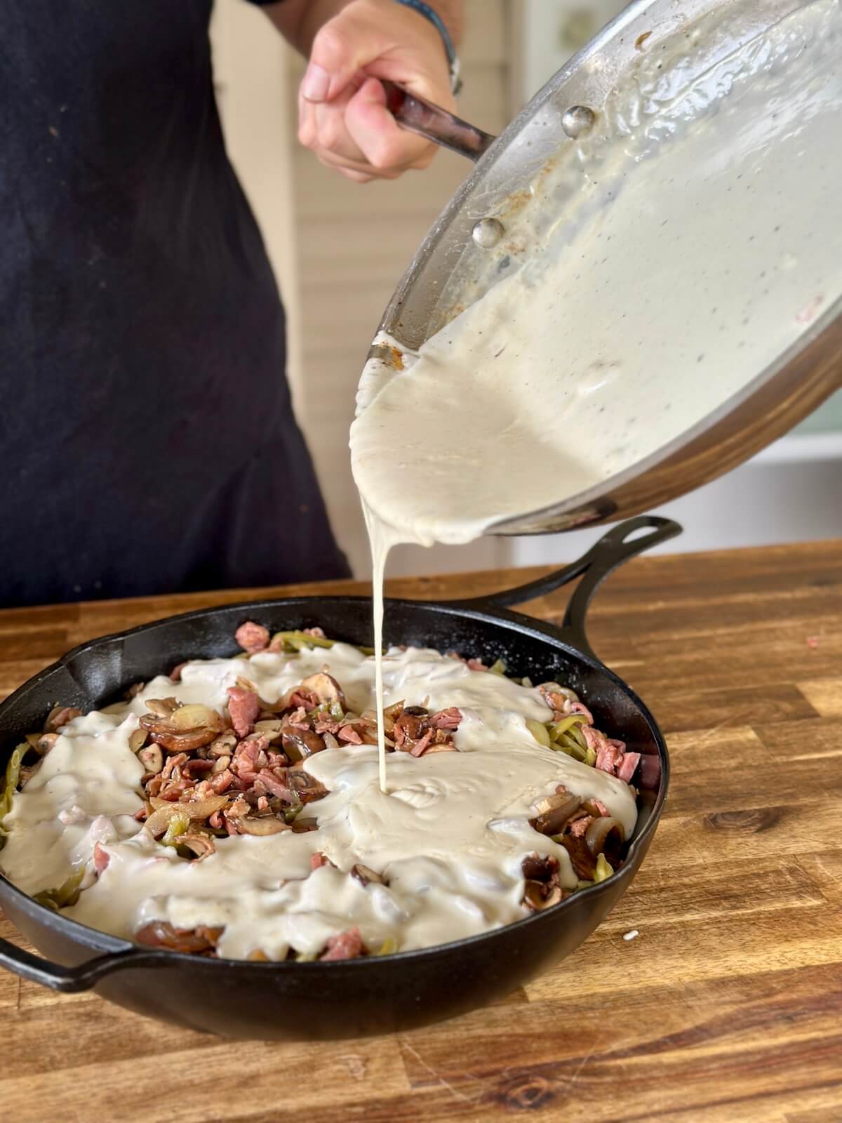 pouring homemade sauce into a green bean casserole