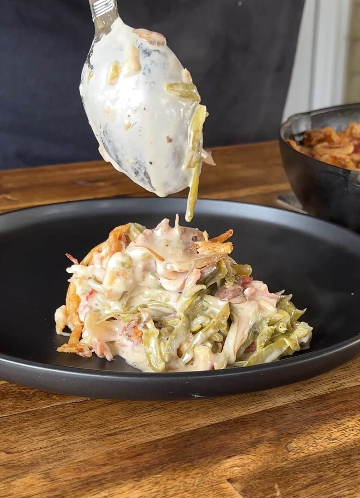 spooning smoked green bean casserole on a plate