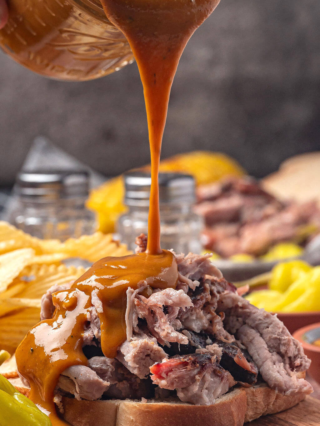 pouring Carolina Gold BBQ sauce onto pulled pork