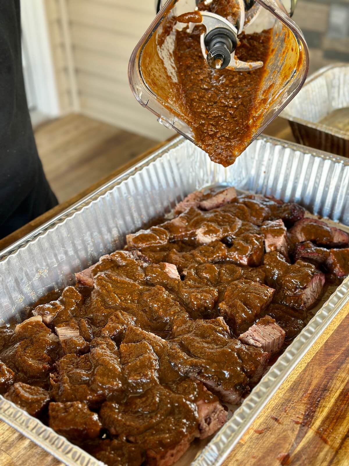 pouring birria sauce over brisket burnt ends