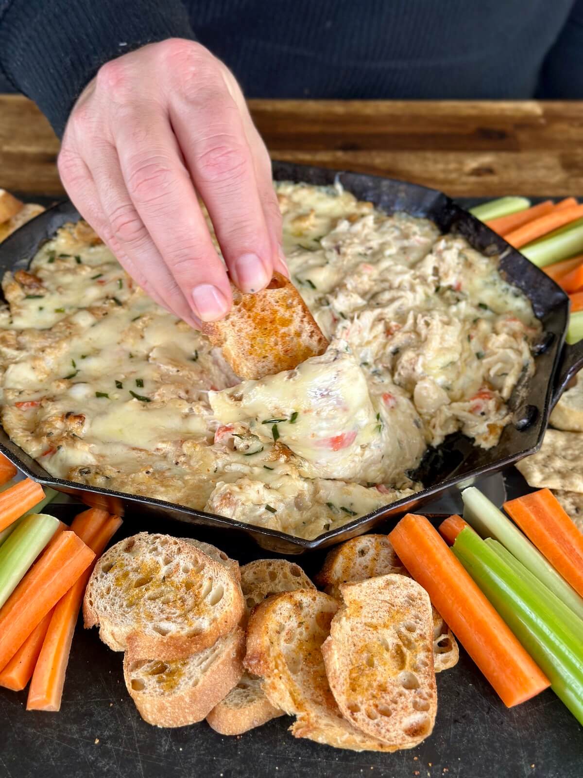 dipping a crostini in smoked crab dip