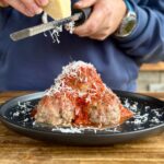 adding parmesan cheese to smoked Italian meatballs
