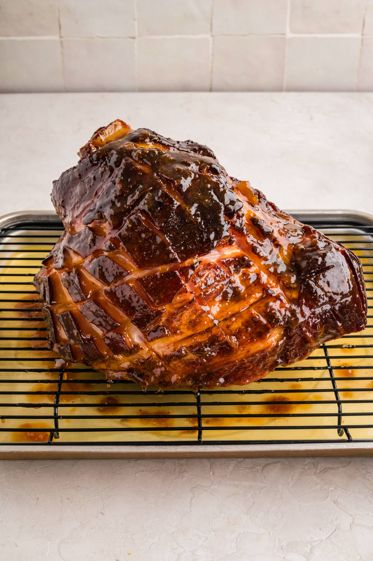 smoked ham on top of a wire cooling rack on a sheet tray with fruit juice underneath