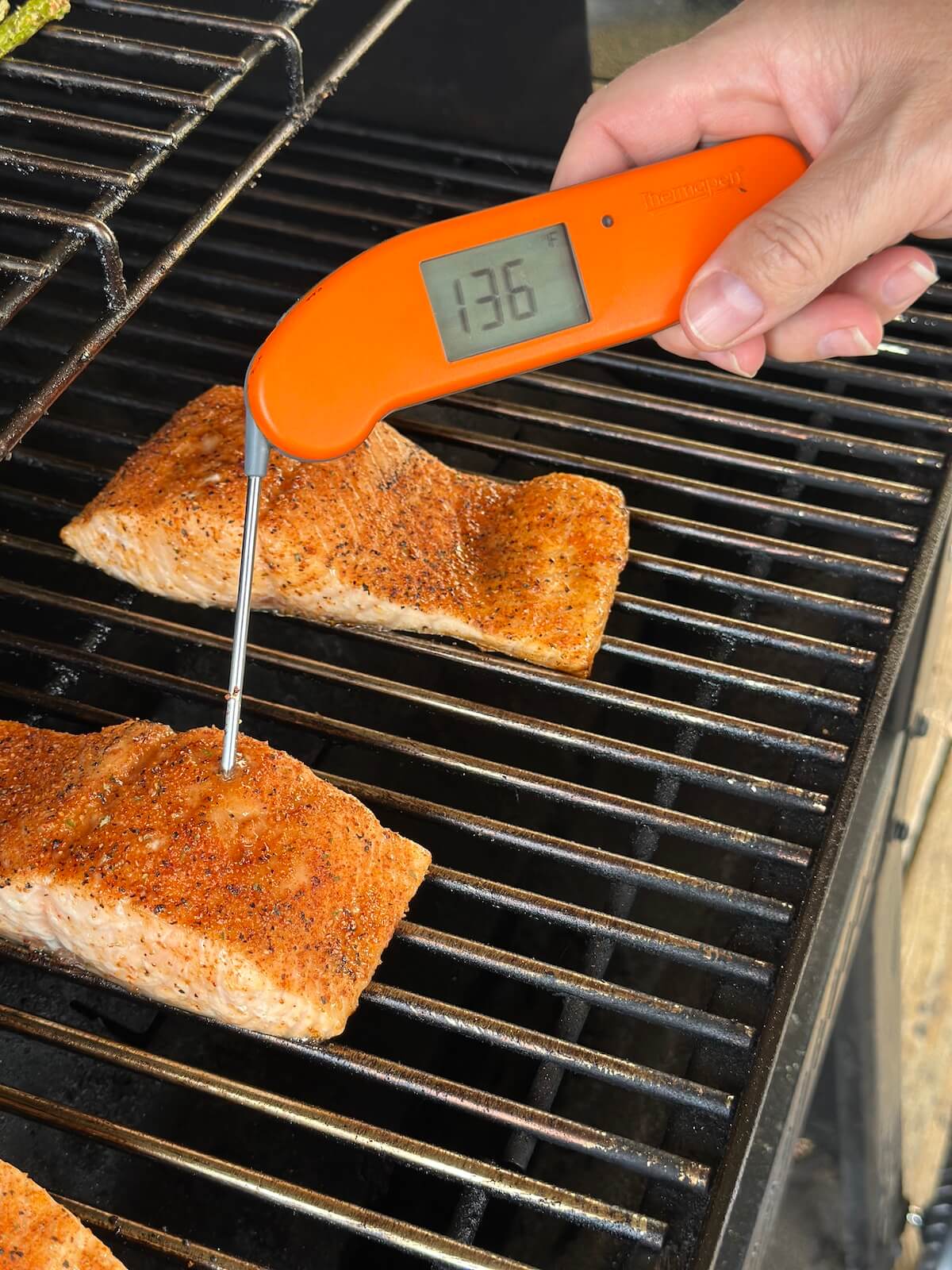 checking internal temperature of pellet grilled salmon with a meat thermometer