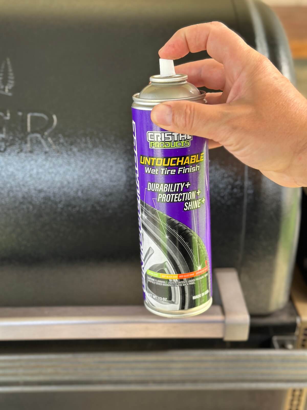 using aerosol spray can of tire cleaner to clean the outside black parts of a Traeger pellet grill