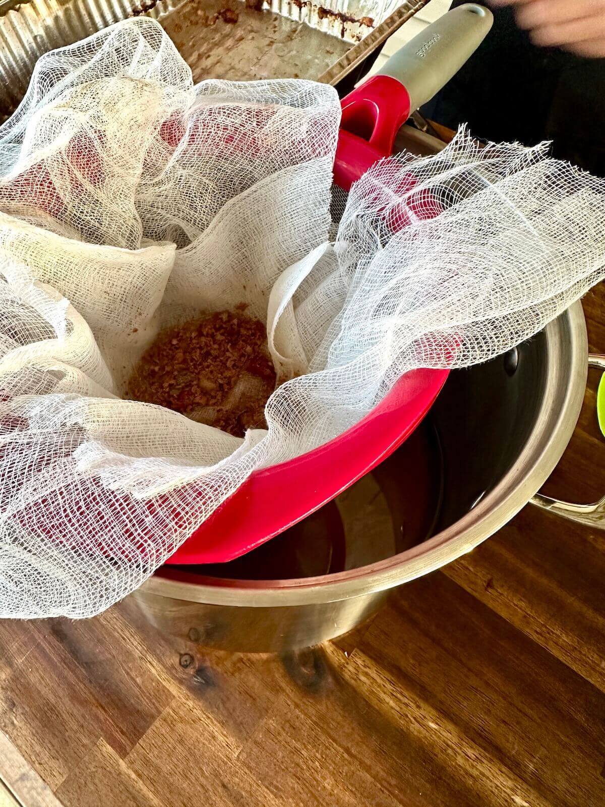 straining liquid beef tallow with a fine mesh strainer and cheesecloth