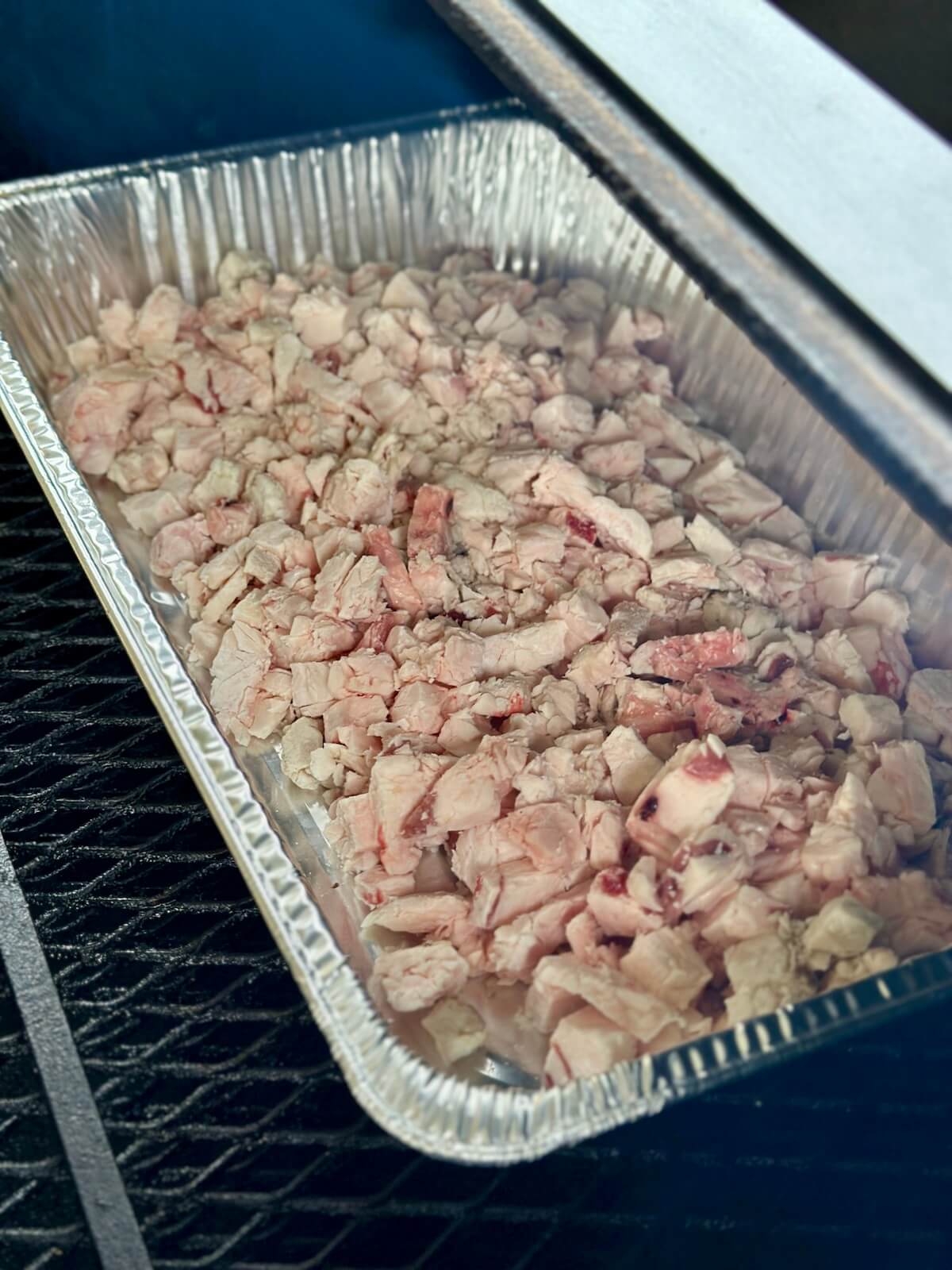 cut brisket fat in a disposable aluminum foil pan smoking on a pellet grill