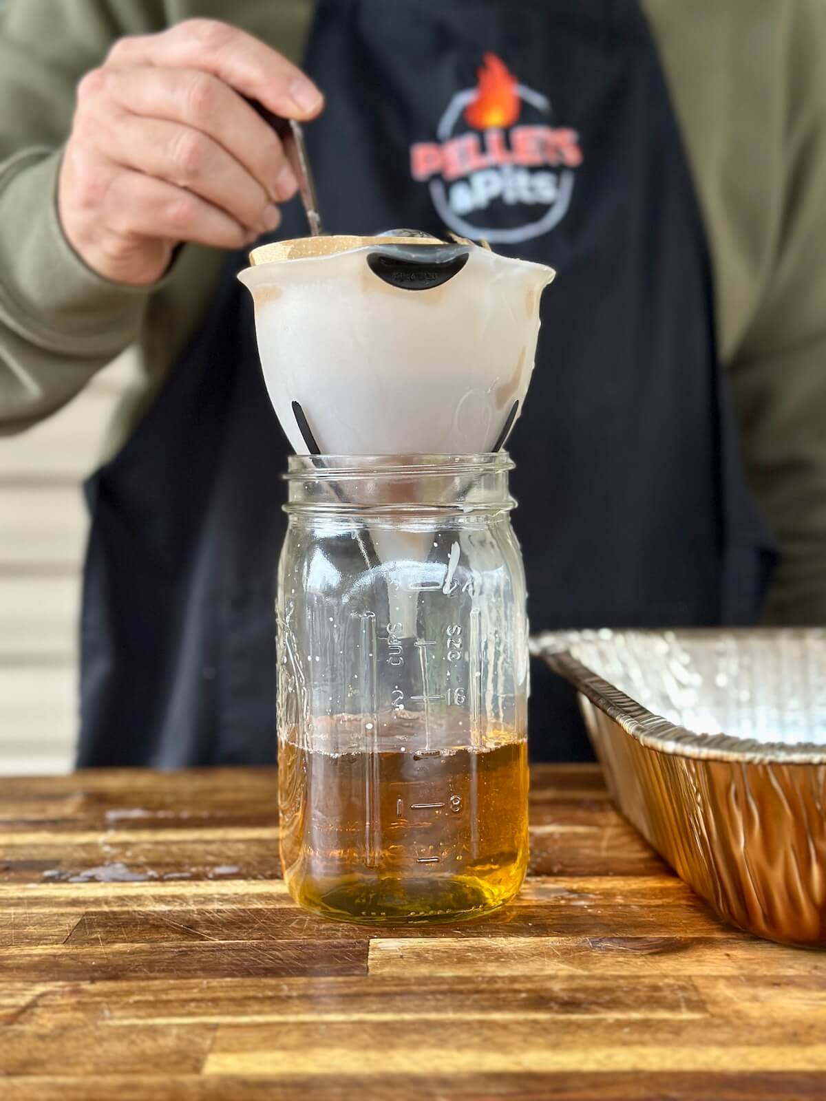 straining liquid beef tallow in a funnel with a coffee filter into a mason jar