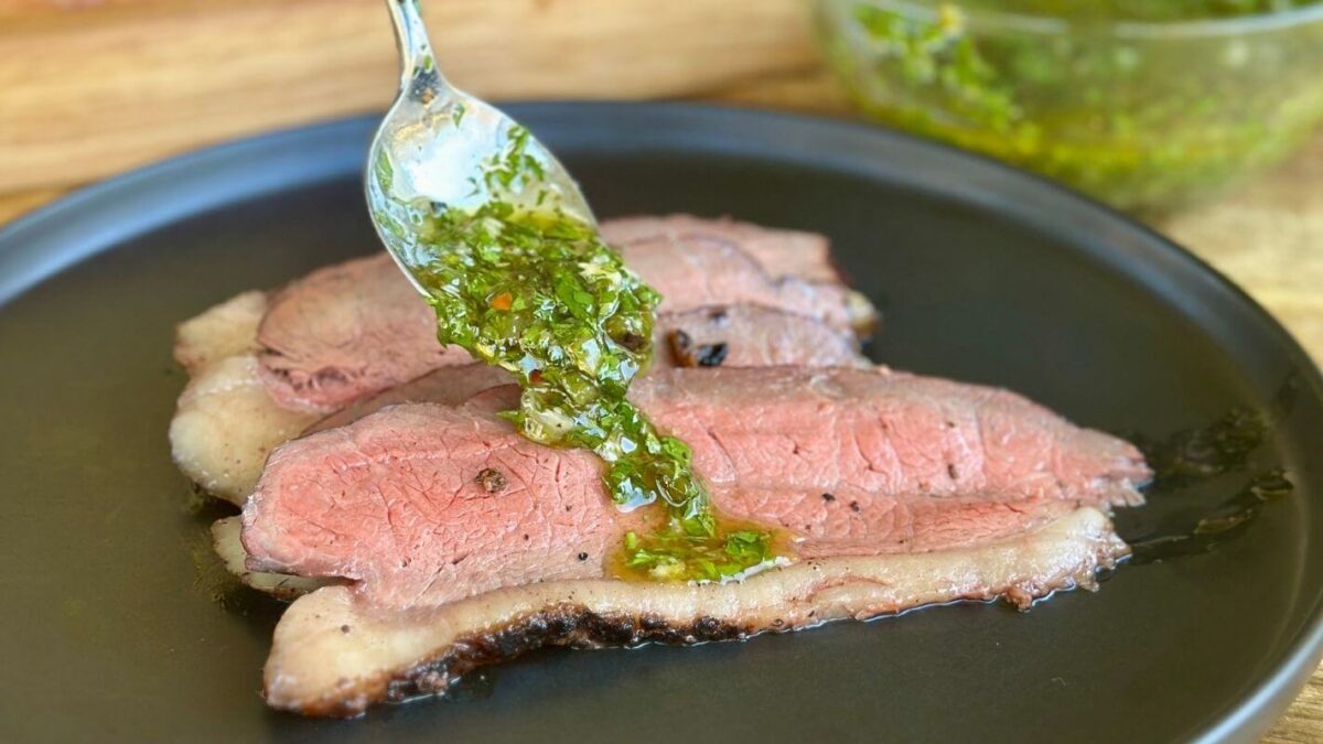 spooning chimichurri on to sliced smoked picanha