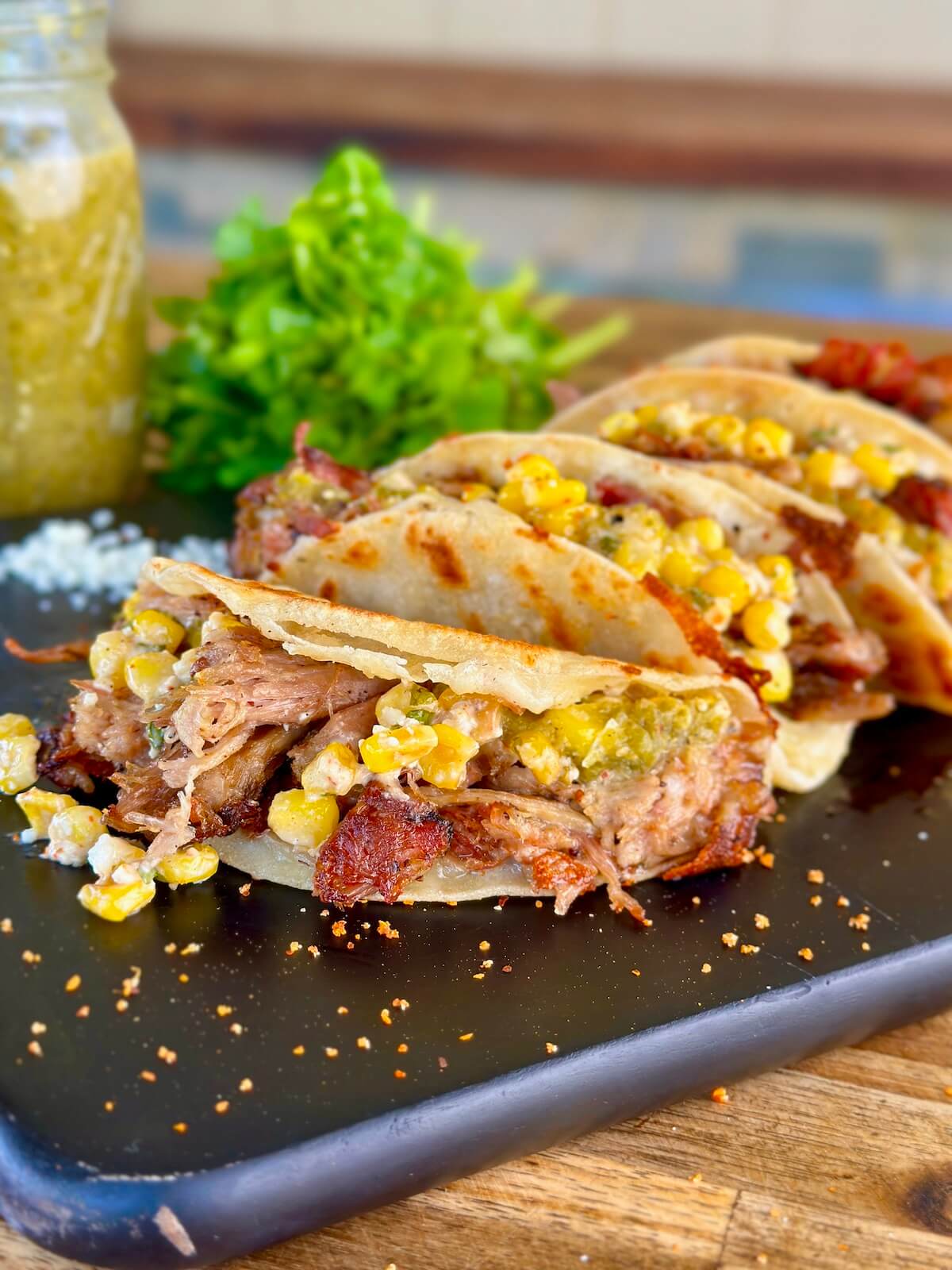 pulled pork tacos with Mexican street corn and tomatillo salsa on corn tortillas