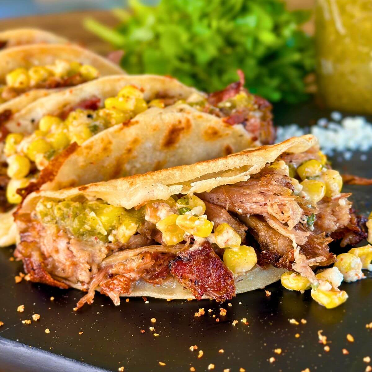 pulled pork tacos with Mexican street corn and tomatillo salsa on corn tortillas