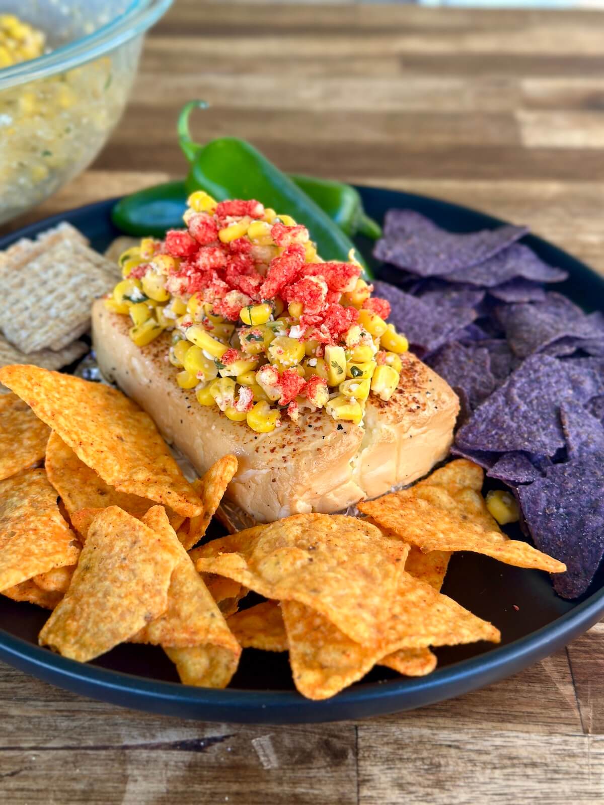 smoked cream cheese topped with Mexican street corn on a serving platter with crackers and cheese Doritos