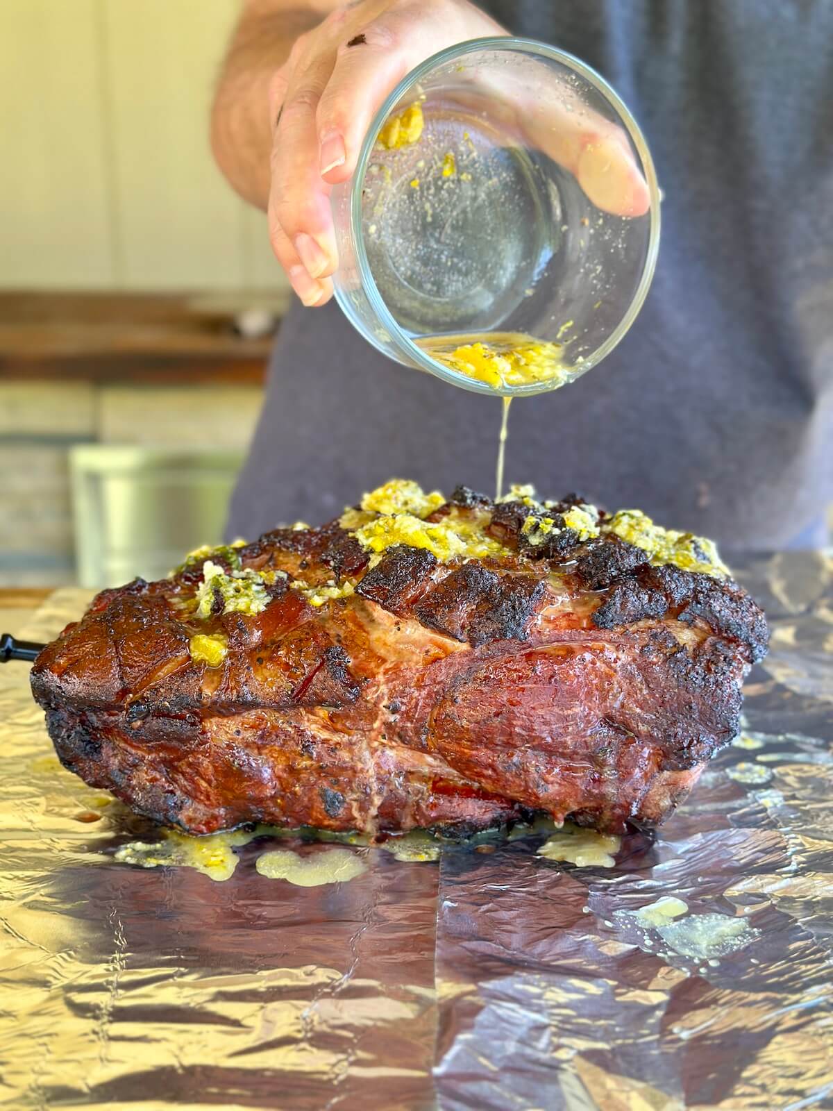 pouring mojo marinade on a smoked pork butt