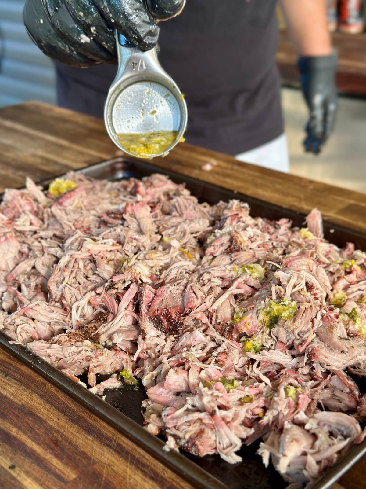 drizzling mojo sauce on smoked pulled pork
