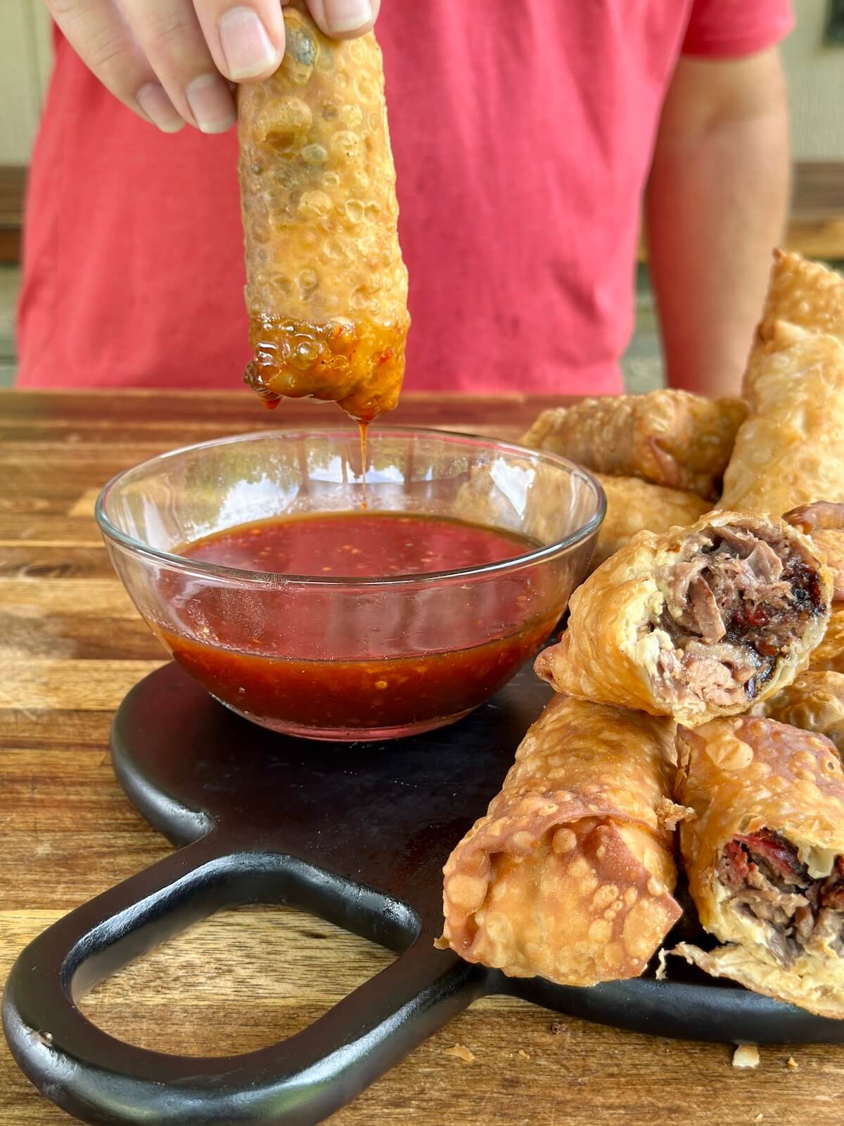 dipping a brisket egg roll into a bbq dipping sauce