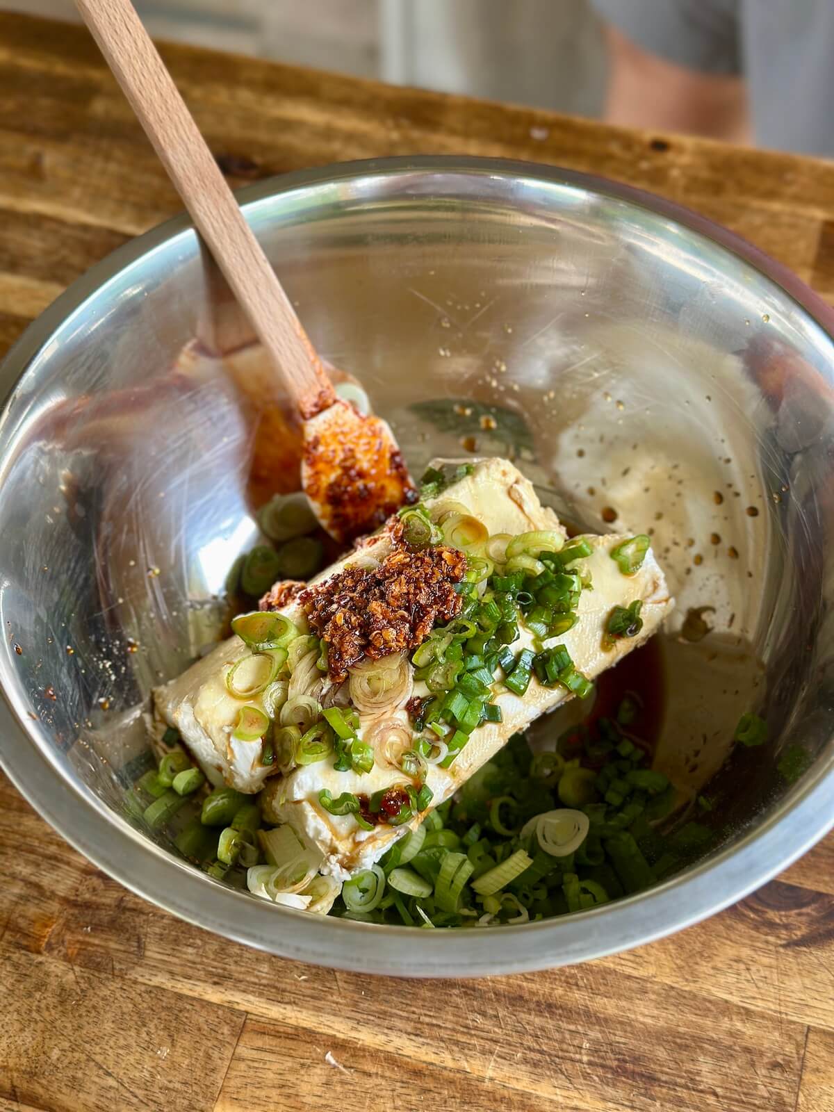 cream cheese, thinly sliced green onions, and chili crisp in a mixing bowl