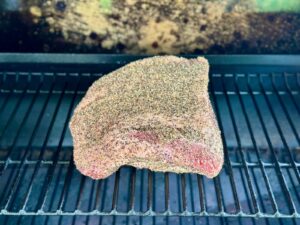 seasoned brisket point on the grill grate of a pellet grill