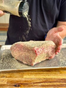 seasoning a brisket point with a blend of salt, black pepper, garlic powder, and seasoned salt