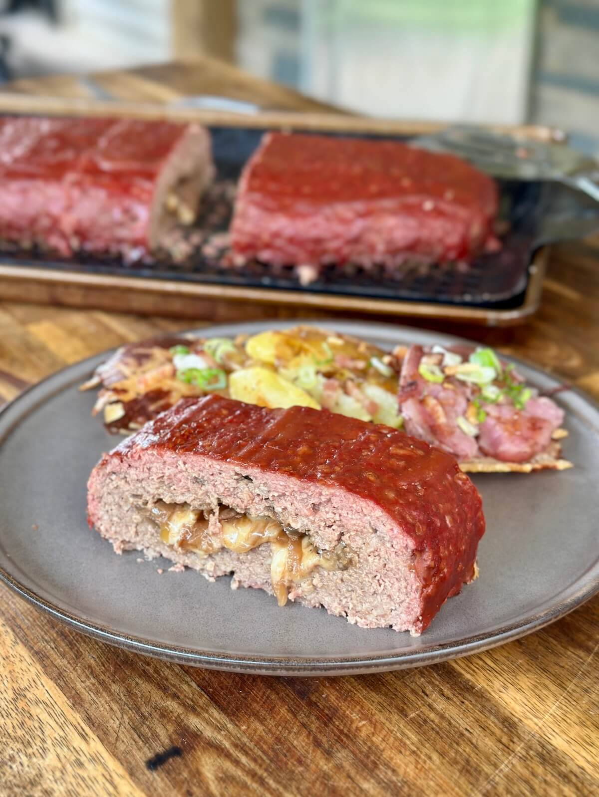slice of French onion stuffed meatloaf on a plate with smashed potatoes