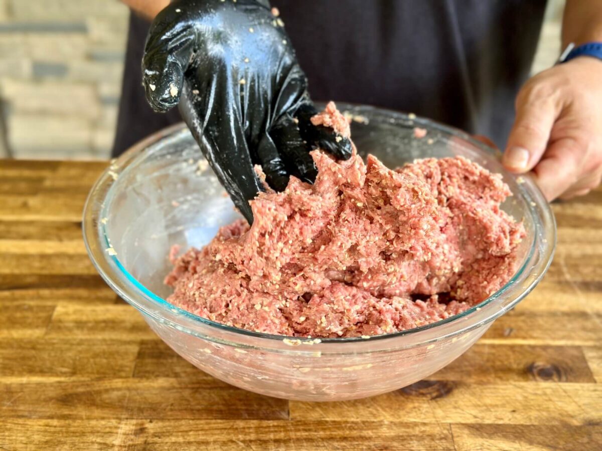 mixing ground beef and other ingredients in a mixing bowl