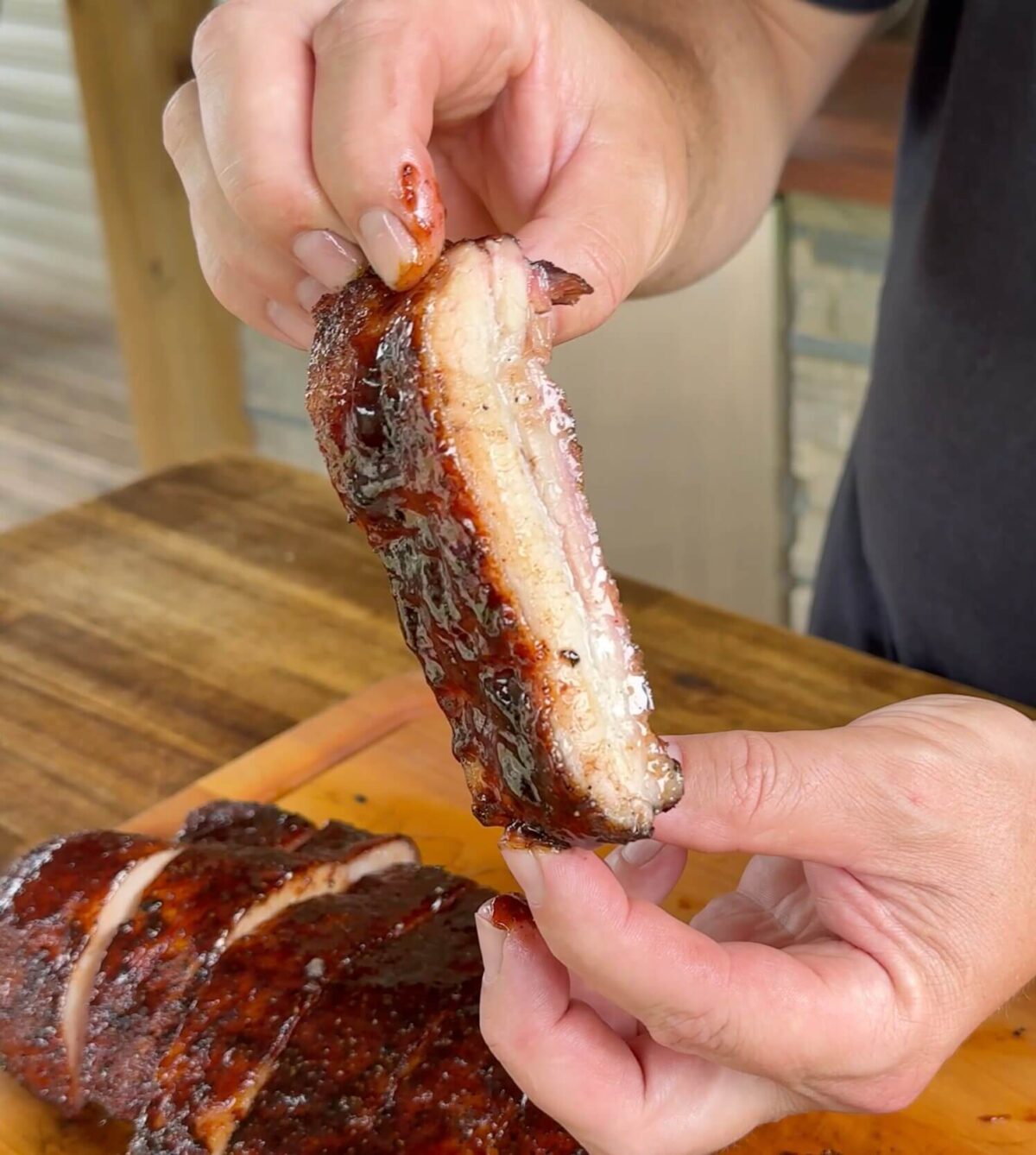 a piece of smoked pork belly with barbecue sauce that is cut into a rib shape