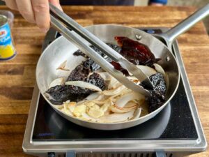 sauteeing onions and dried chile peppers in a skillet
