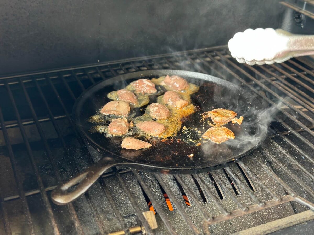 cooking dove breasts in a cast iron skillet on a grill
