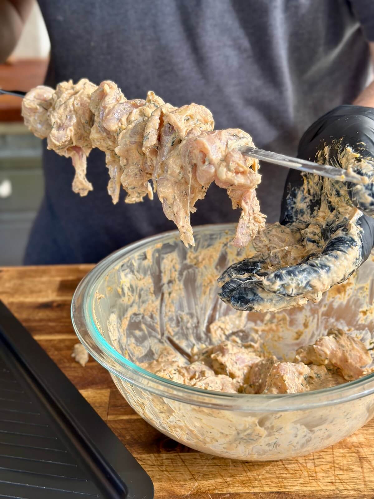 placing long thin strips of marinated chicken on a metal skewer