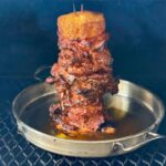 grilling al pastor pork shoulder on a vertical skewer on a pellet grill