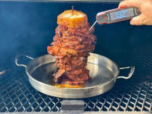 using an instant read meat thermometer to check the internal temp of al pastor on a skewer