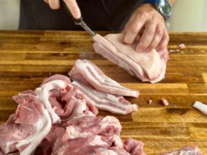 slicing a pork butt into thin slices