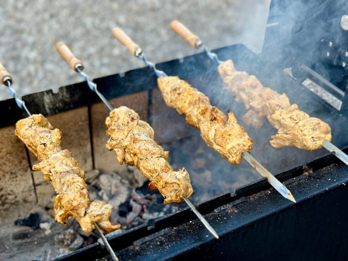 grilling Greek chicken skewers over charcoal