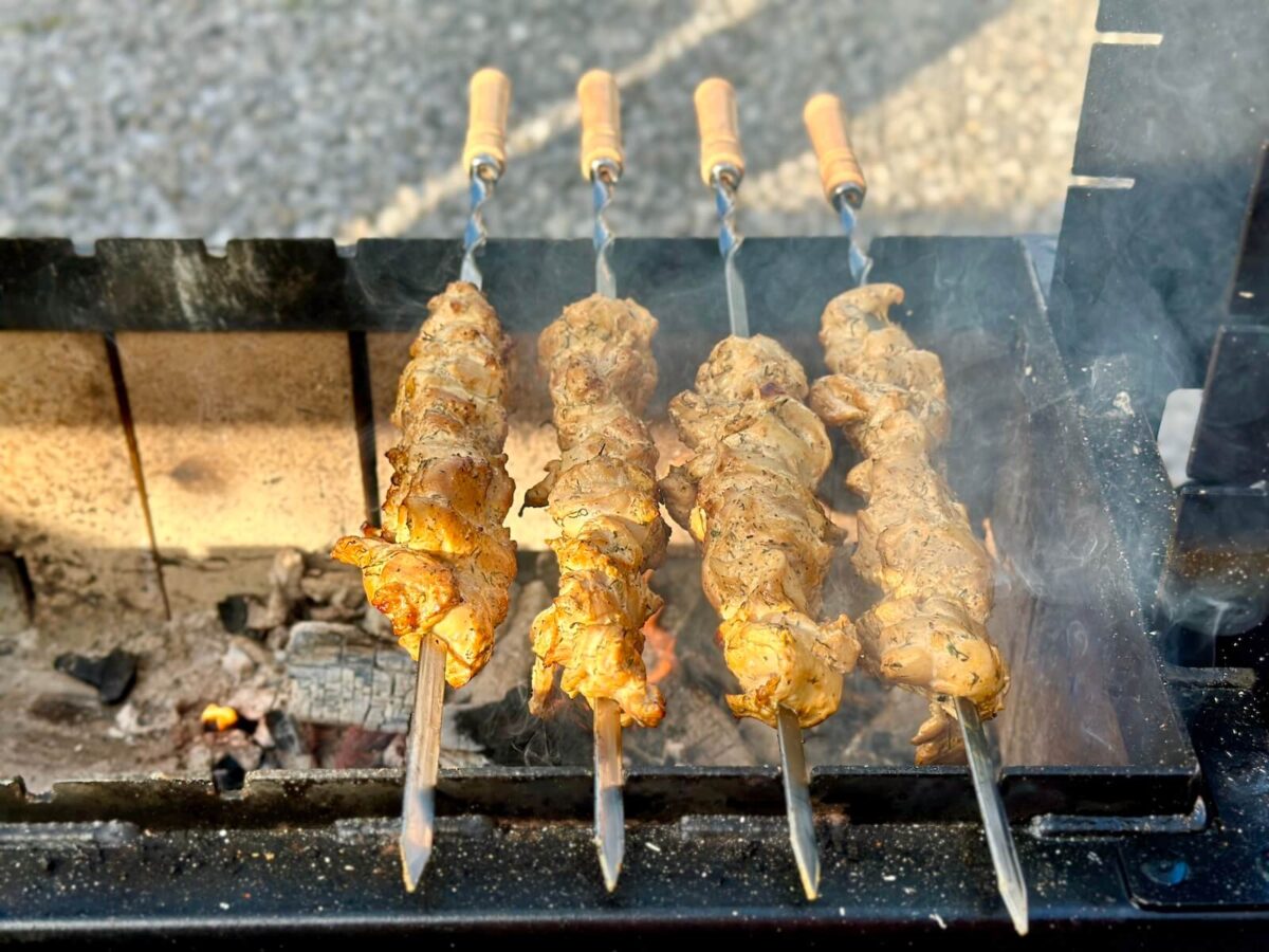 grilling Greek chicken skewers over charcoal