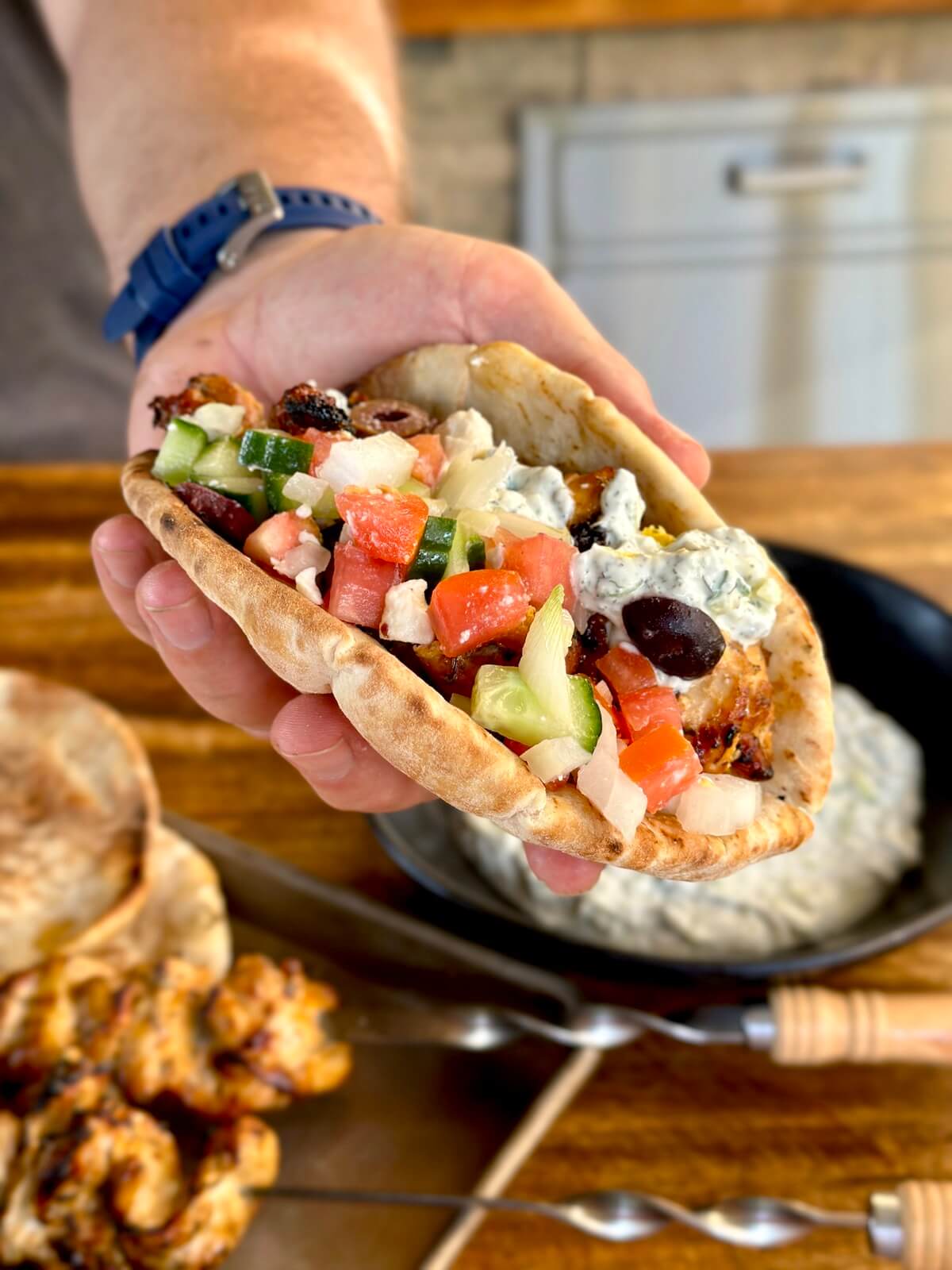 a Greek chicken pita with grilled chicken, feta cheese, tzaziki, diced cucumbers, and diced tomatoes
