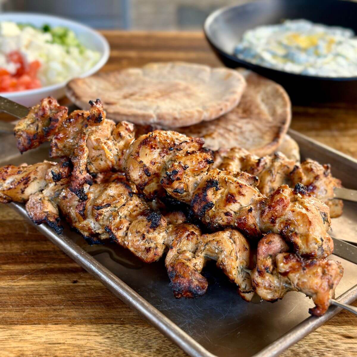 grilled Greek chicken skewers with pita, tzaziki, and diced tomato