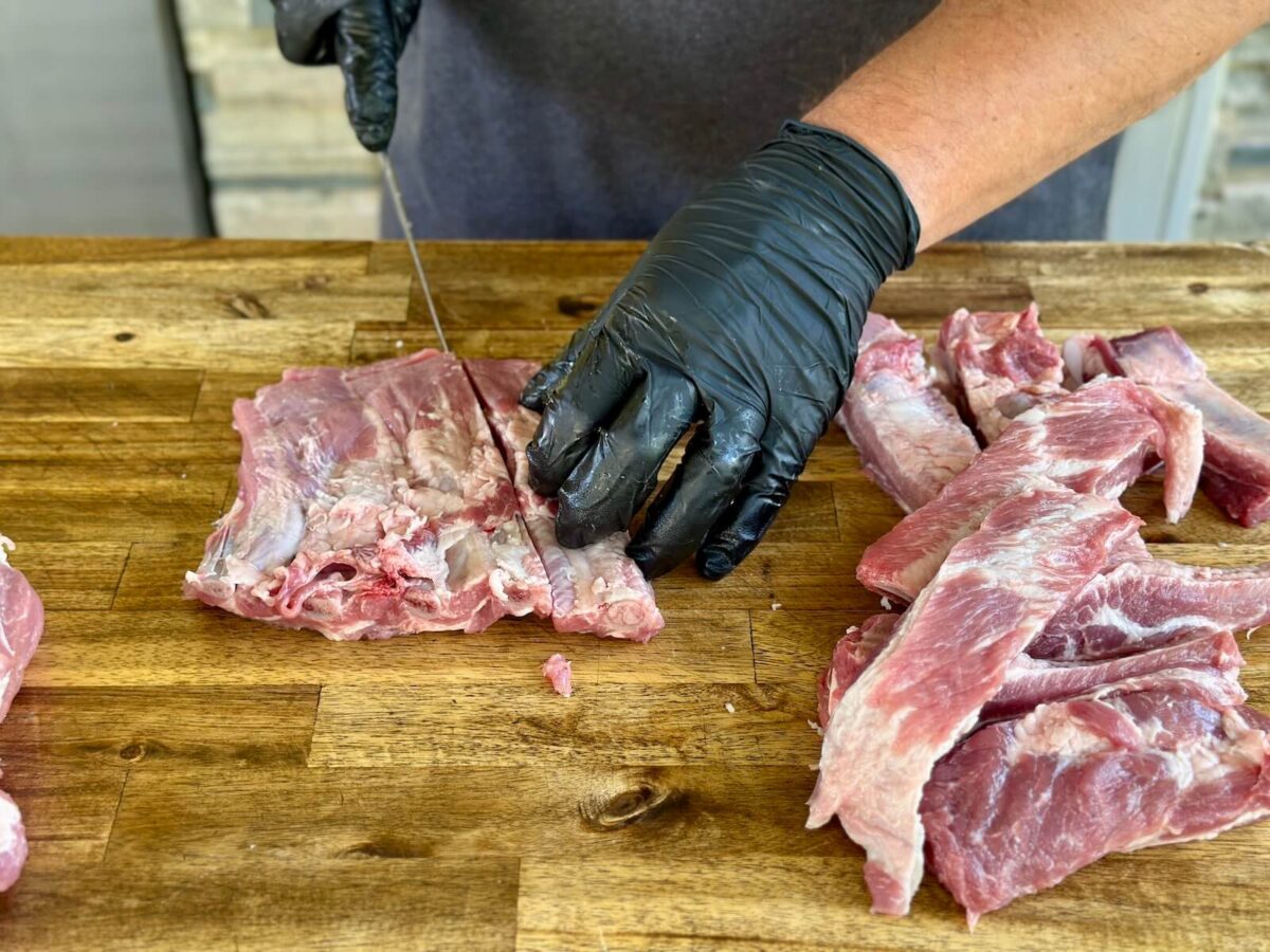 cutting a slab of pork ribs into individual rib pieces