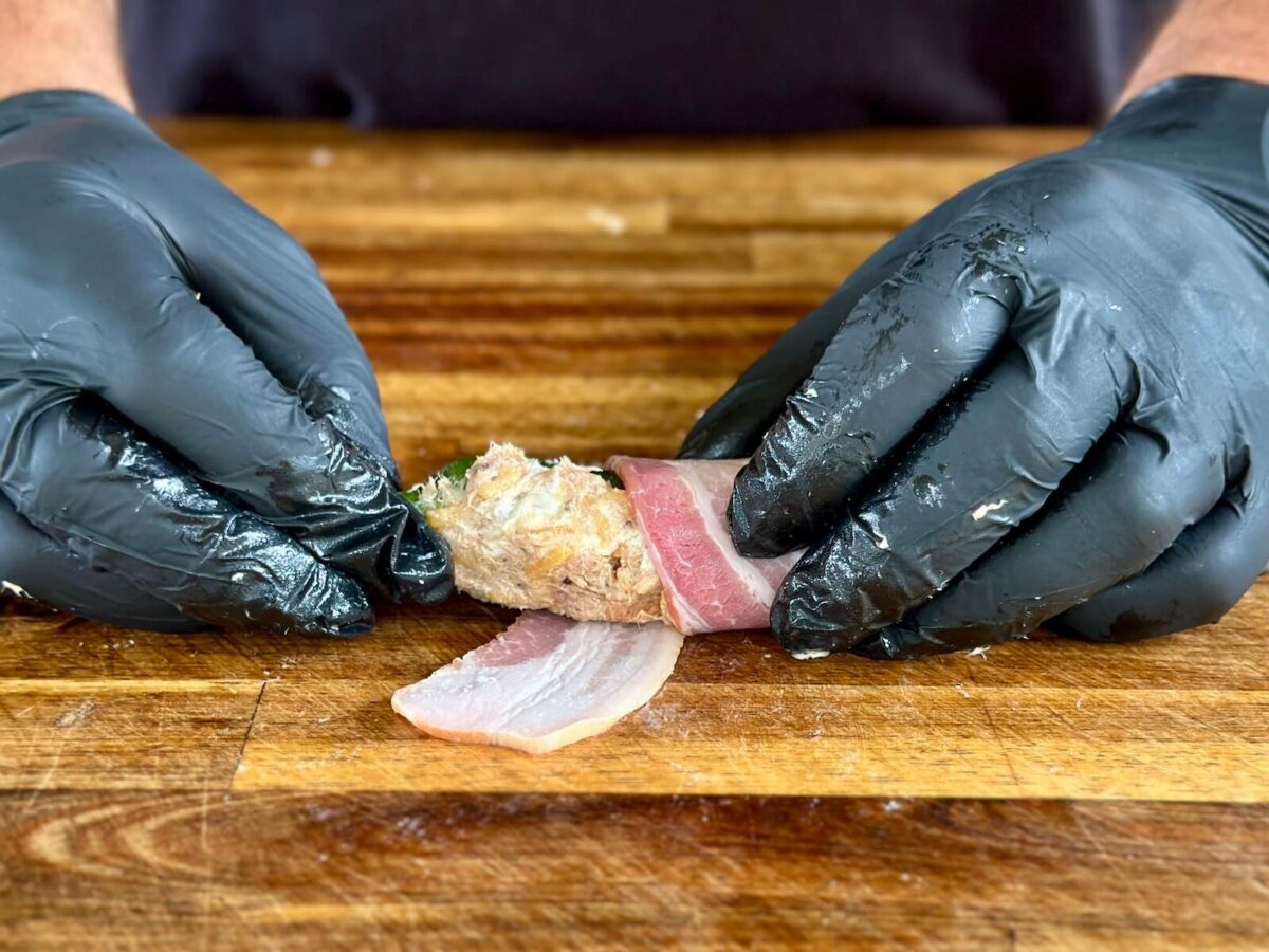 wrapping a cream cheese and pulled pork stuffed jalapeno in bacon
