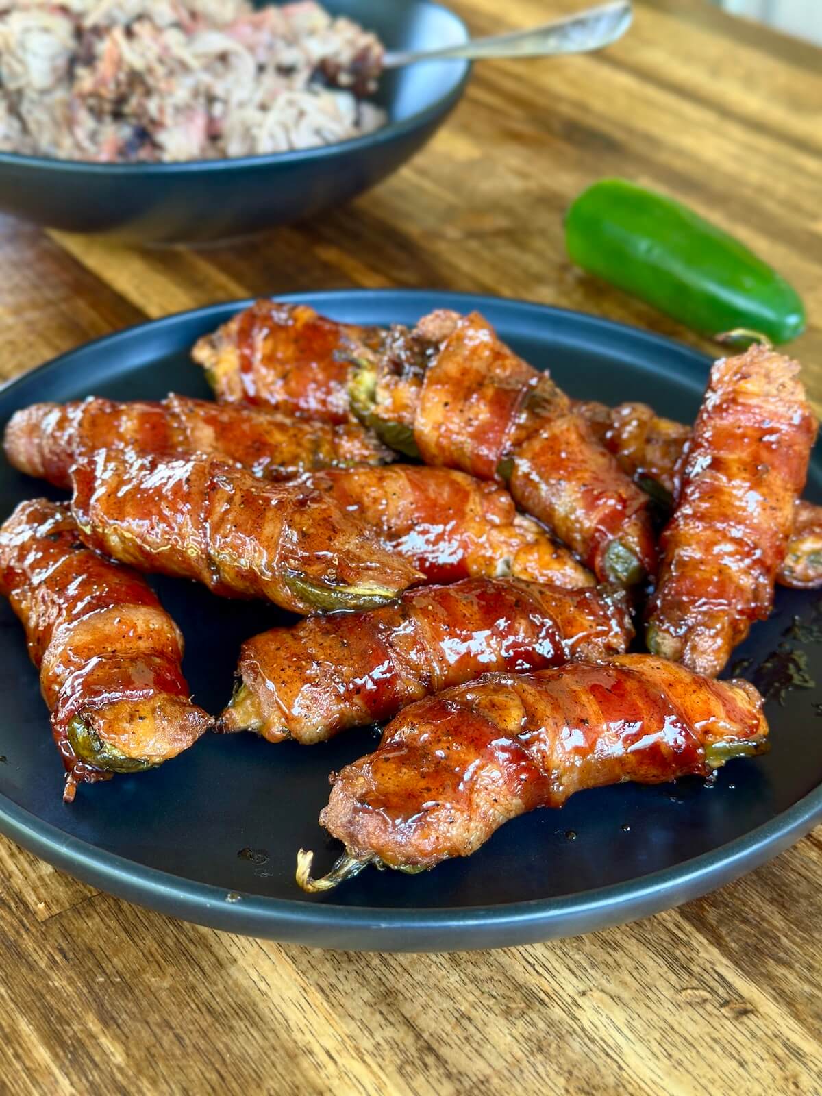 bacon wrapped pulled pork jalapeno poppers on a plate