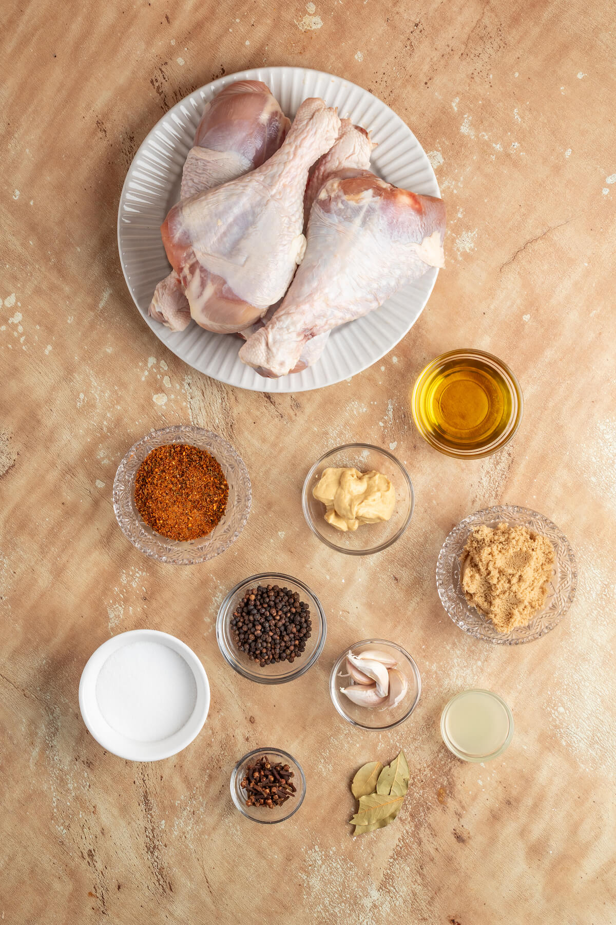 raw turkey legs with spices measured out in bowls