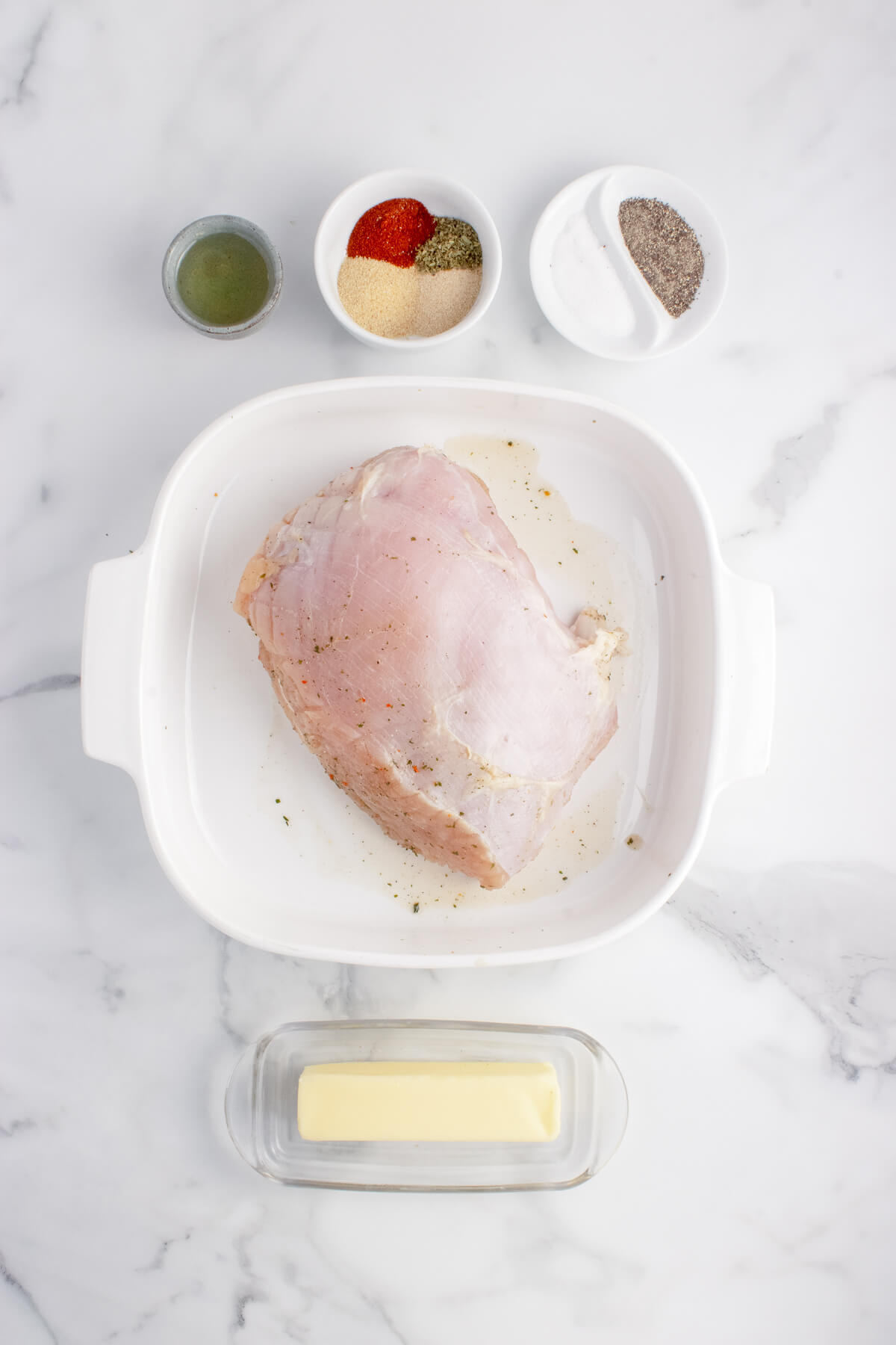 raw turkey breast, stick of butter, and spices and dried herbs measured out in small cups