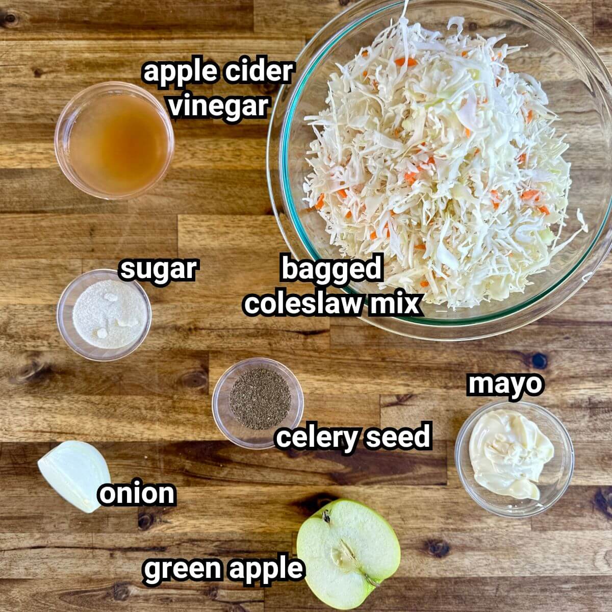 ingredients for coleslaw including bagged cabbage mix, apple cider vinegar, mayo, sugar, celery seed, and green apple