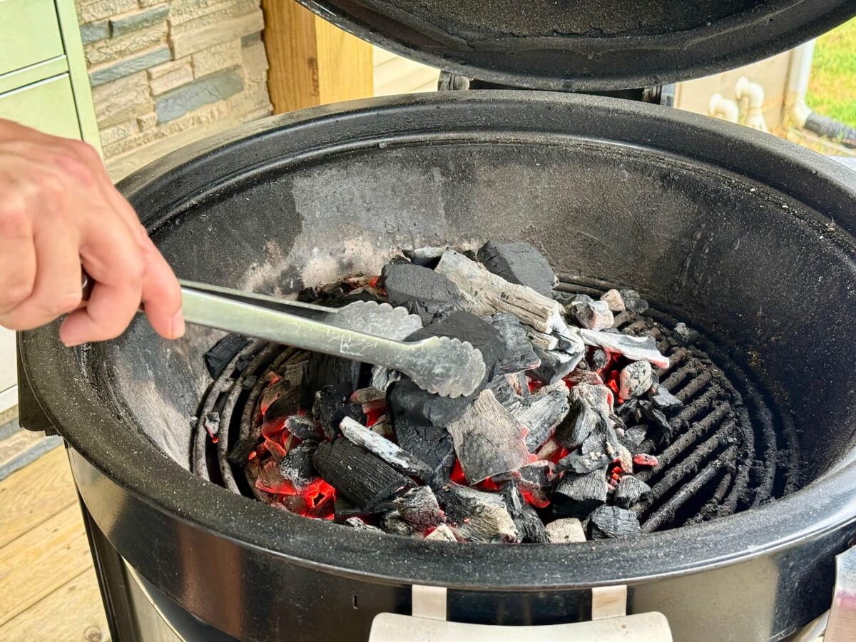 moving lit coals in a kettle style charcoal grill for direct heat hot and fast grilling