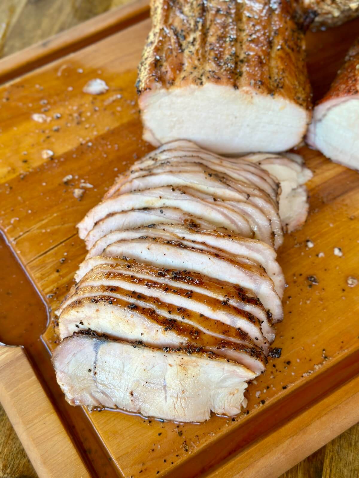 a whole smoked pork loin sliced on a cutting board