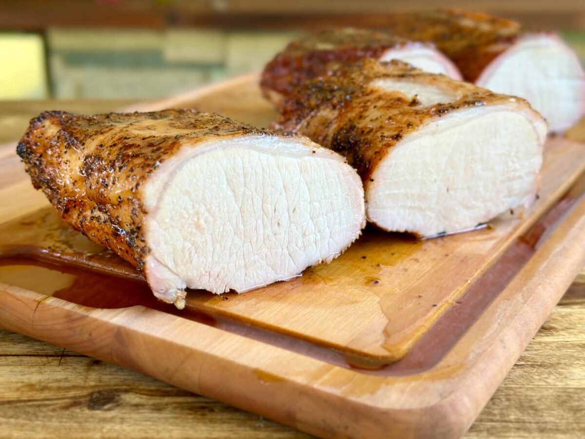 juicy smoked pork loin cut in half on a cutting board